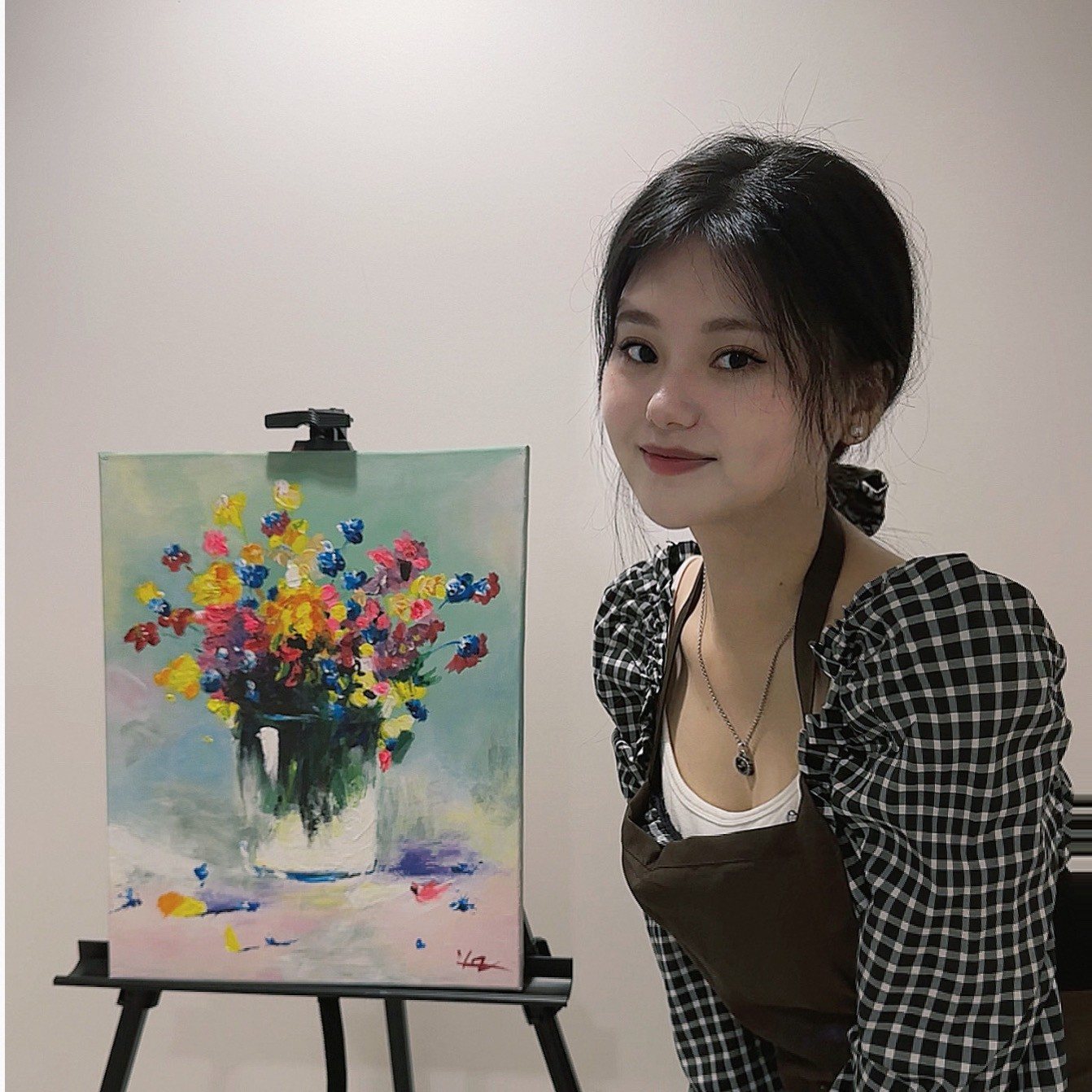 Yuanyi standing next to one of her acrylic flower paintings on an easel